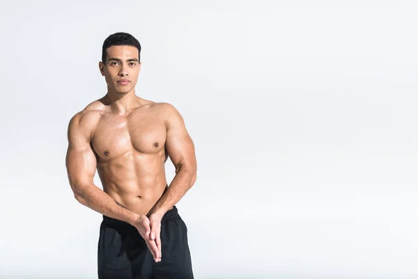 Handsome athletic mixed race man with folded hands looking at camera on white — Stock Photo