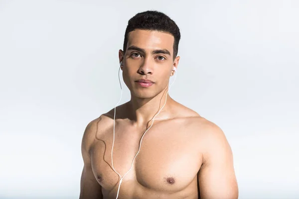 Bonito atlético homem com muscular torso ouvindo música em fones de ouvido no branco — Fotografia de Stock