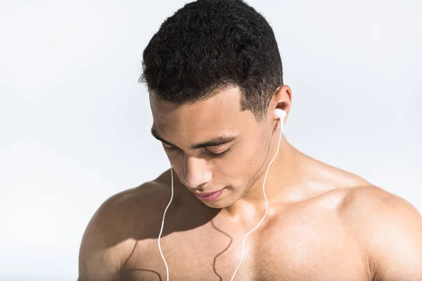 Bonito sem camisa misto raça homem ouvindo música em fones de ouvido no branco — Fotografia de Stock