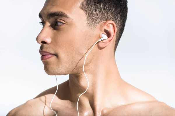 Handsome shirtless mixed race man listening music and looking away on white — Stock Photo