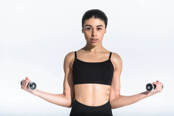 Pretty sportive african american girl in black sports bra training with dumbbells on white — Stock Photo
