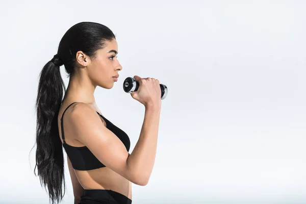 Visão lateral de treinamento menina afro-americano bastante esportivo com halteres em branco — Fotografia de Stock