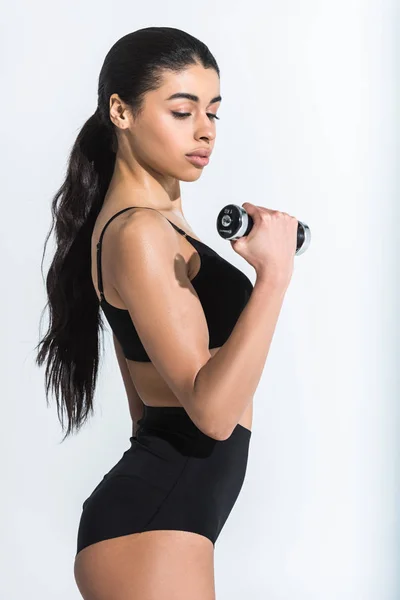 Séduisante jeune femme afro-américaine en formation de vêtements de sport noirs avec haltère sur blanc — Stock Photo