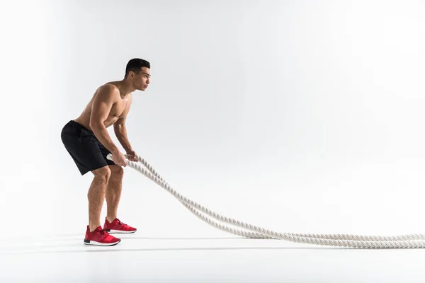 Esportivo misto raça homem no preto shorts e tênis vermelho segurando cordas no branco — Fotografia de Stock