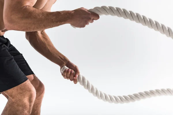 Visão parcial do homem esportivo fazendo exercício com cordas no fundo branco — Fotografia de Stock