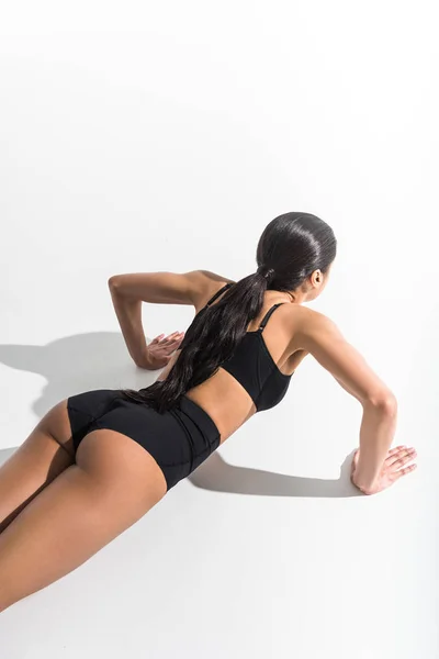 Overhead view of athletic african american girl doing push ups on white — Stock Photo