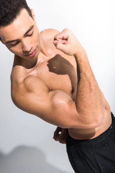 Beau sportif mixte homme démontrant biceps sur fond blanc — Photo de stock