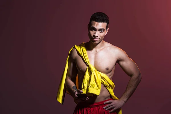 Handsome sportive mixed race man with hand on hip posing on dark background — Stock Photo