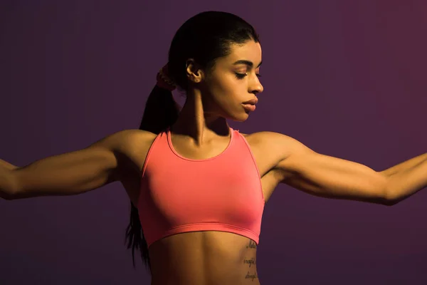 Pretty athletic african american girl in pink sports bra isolated on purple — Stock Photo