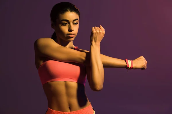 Bella atletica ragazza africana americana riscaldamento isolato su viola — Foto stock