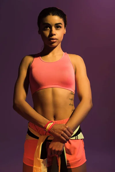 Pretty sportive african american girl in pink sports bra isolated on purple — Stock Photo