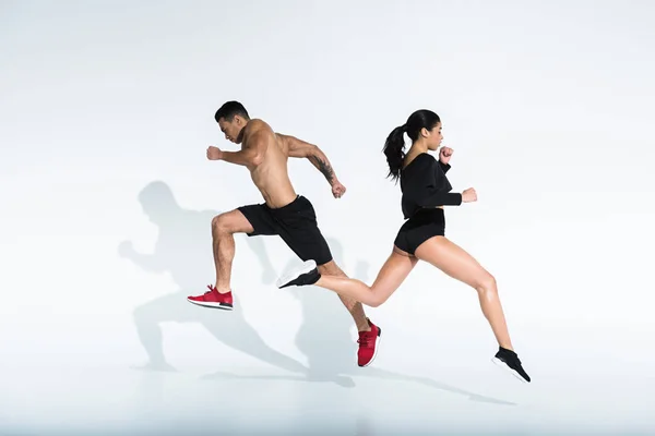 Sportive african american girl and athletic mixed race man running on white background — Stock Photo