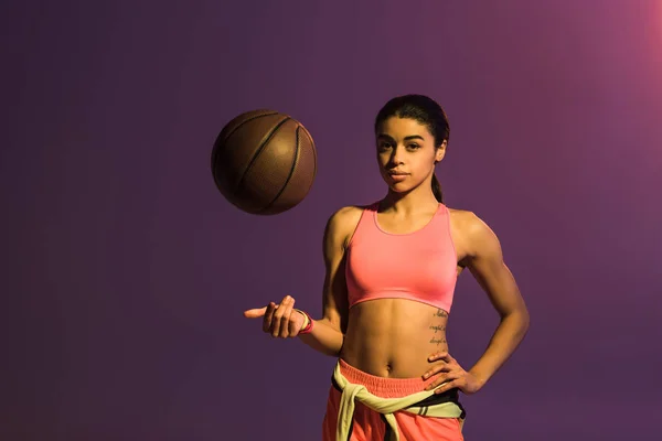 Attrayant sportif afro-américain fille avec boule brune regardant la caméra sur fond violet — Photo de stock