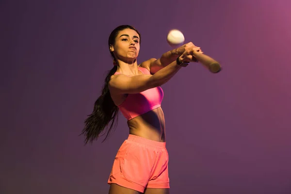 Sportive african american girl in pink sports bra playing baseball on purple background — Stock Photo
