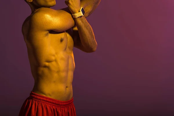 Abgeschnittene Ansicht eines sportlichen Mannes in smarter Uhr, der sich auf lila Hintergrund aufwärmt — Stockfoto