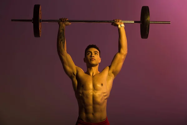 Bello atletico misto corsa uomo sollevamento bilanciere su sfondo viola — Foto stock