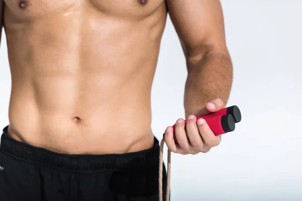 Vista recortada del hombre con torso muscular que sostiene la cuerda de salto en blanco - foto de stock