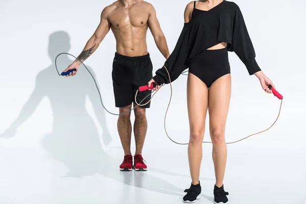 Vista parcial del hombre y la mujer multiculturales con saltar cuerdas en blanco - foto de stock