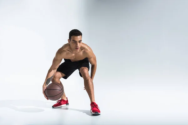 Atletico uomo gara mista in scarpe da ginnastica rosse giocare a palla su sfondo bianco — Foto stock