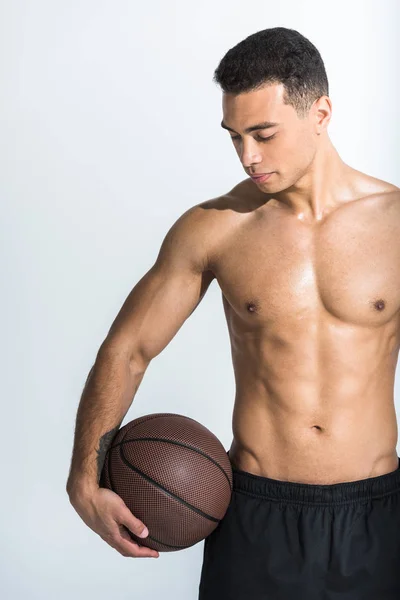 Bel homme de race mixte sportif avec torse musculaire tenant la balle brune sur blanc — Photo de stock