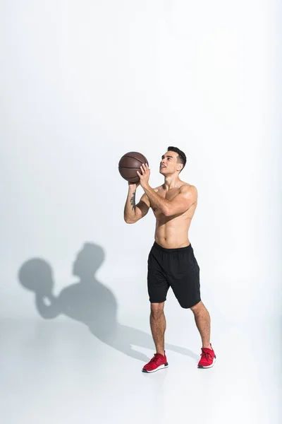 Красивый спортивный мужчина смешанной расы, играющий в мяч на белом фоне — стоковое фото