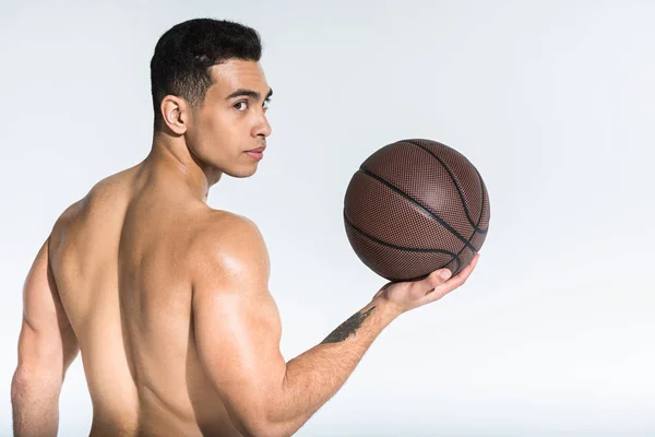 Bel homme de course mixte athlétique avec torse musculaire tenant la balle brune sur blanc — Photo de stock