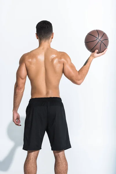 Visão traseira do homem atlético em shorts pretos segurando bola marrom no branco — Fotografia de Stock
