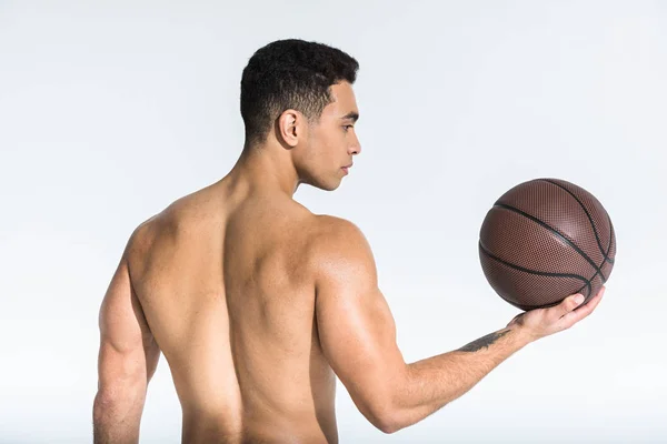 Athletischer Mischlingsmann mit muskulösem Oberkörper, der braunen Ball auf weißem Grund hält — Stockfoto