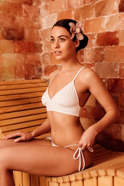 Mince jeune femme en maillot de bain regardant loin dans le sauna — Photo de stock