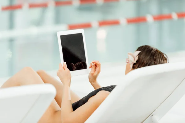 Junge Frau benutzt digitales Tablet, während sie im Wellness-Center auf der Sonnenliege liegt — Stockfoto