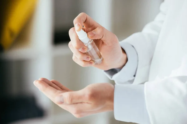 Vista recortada del médico aplicando aerosol antibacteriano en la mano en el hospital - foto de stock