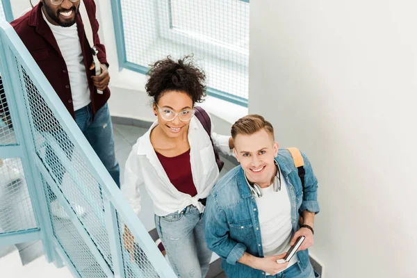 Vista aerea di tre studenti multietnici sorridenti con zaini — Foto stock