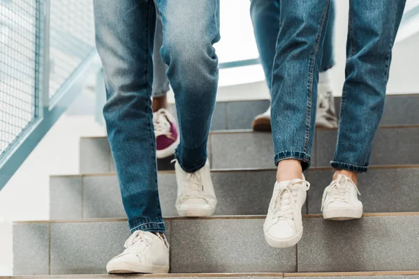 Partial view of group of people in jeans on stairs — Stock Photo