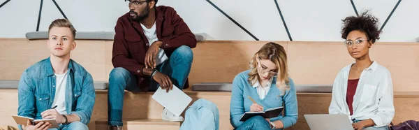 Plano panorámico de cuatro estudiantes multiculturales que estudian en la sala de conferencias - foto de stock