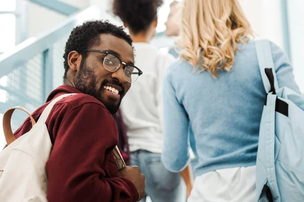 Smiling african american student in glasses with backpack looking at camera — Stock Photo