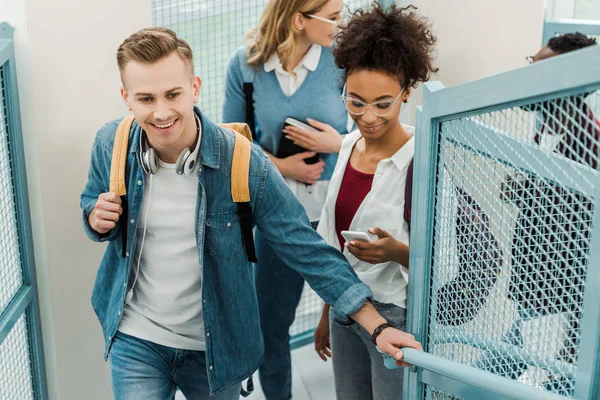 Group of cheerful multicultural students with backpacks in university — Stock Photo