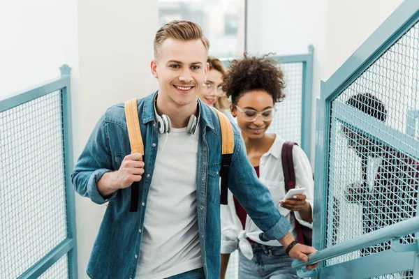 Grupo de alegres estudiantes multiculturales con mochilas en la universidad - foto de stock