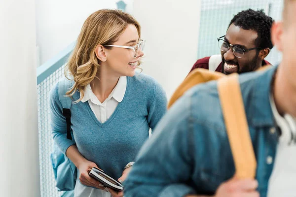 Gruppo di allegri studenti multiculturali con zaini in università — Foto stock