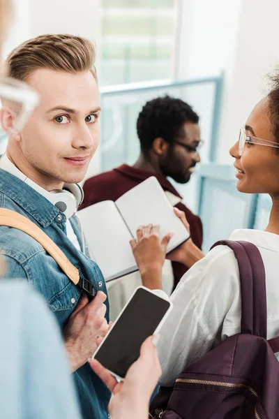 Cropped view of multicultural students with smartphone in university — Stock Photo