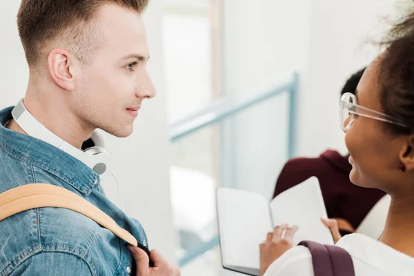 Partial view of multicultural students with notebook in university — Stock Photo