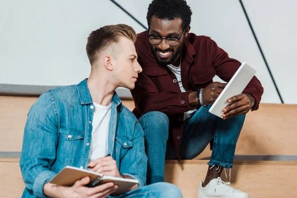 Dos estudiantes multiculturales con portátil y tableta digital en la sala de conferencias — Stock Photo