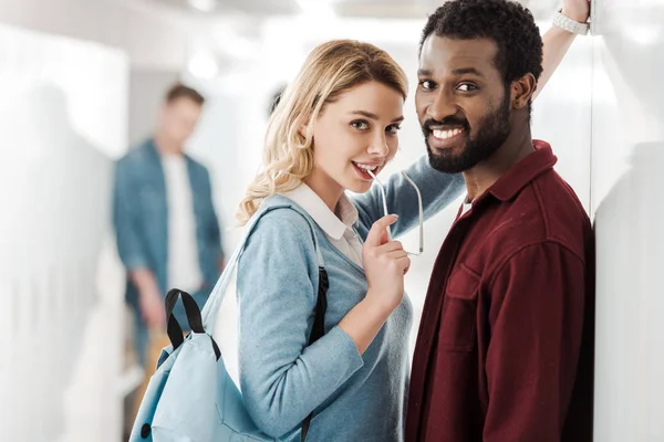 Усміхнені багатоетнічні студенти, що стоять в коридорі в університеті — стокове фото