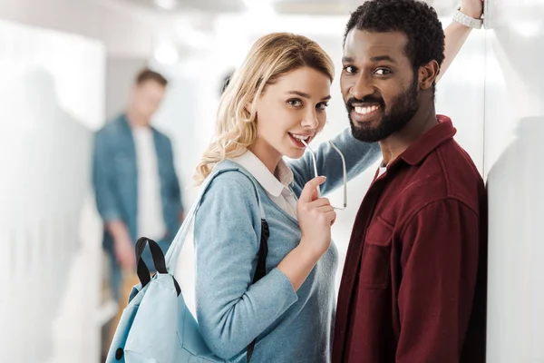 Estudiantes multiétnicos sonrientes de pie en el pasillo en la universidad - foto de stock