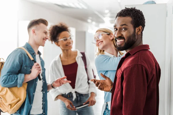 Sorrindo estudantes multiétnicos em pé no corredor na faculdade — Fotografia de Stock