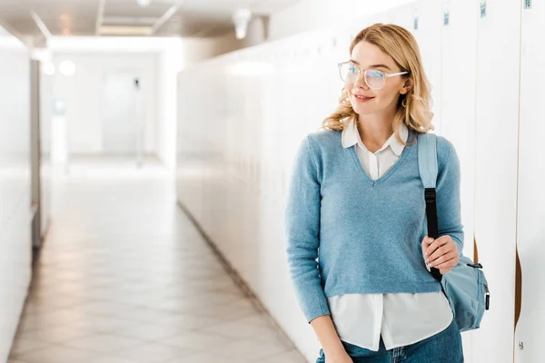 Estudante sorrindo em óculos com mochila no corredor na faculdade — Fotografia de Stock