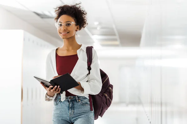 Studente afroamericano con quaderno in corridoio all'università — Foto stock