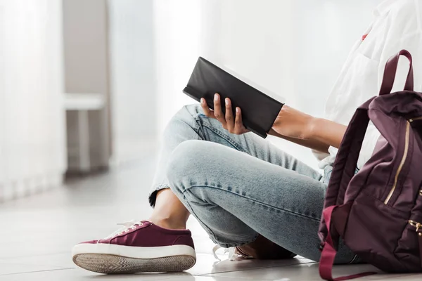 Vista parcial del estudiante con cuaderno sentado en el suelo — Stock Photo