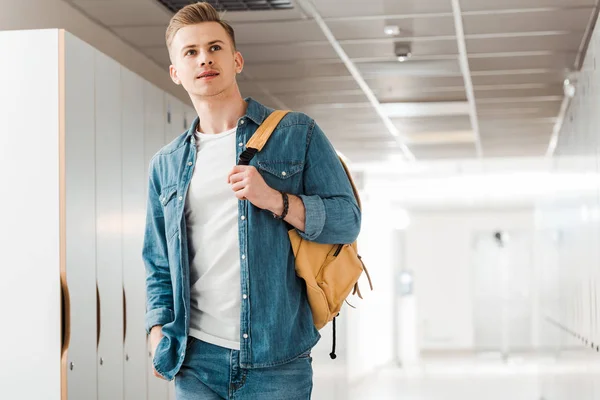 Pensive student with backpack in corridor in university — Stock Photo