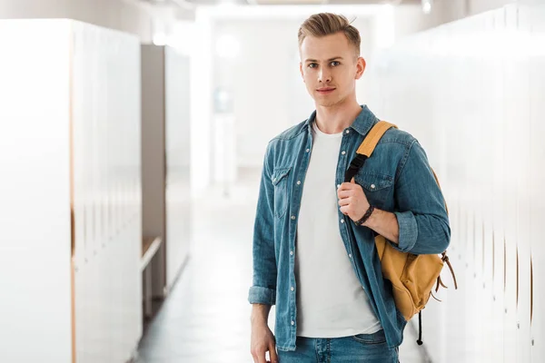 Étudiant avec sac à dos regardant caméra dans le couloir à l'université — Photo de stock