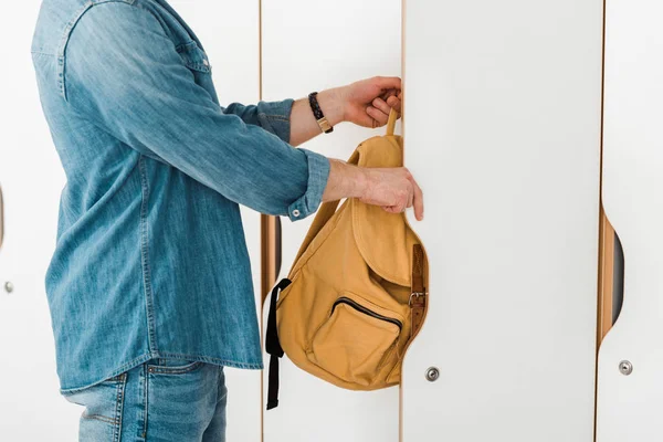 Обрезанный вид студента с рюкзаком открытия шкафчика — стоковое фото